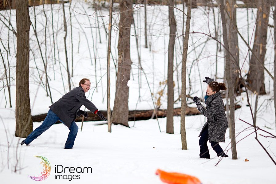 Engaged couple having a snow ball fight
